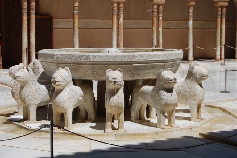 Stone fountain with 12 lion sculptures in a courtyard.