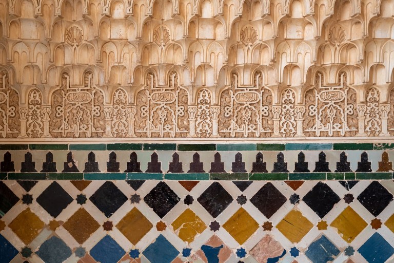 Intricate stone wall with colorful geometric tile pattern at the bottom.