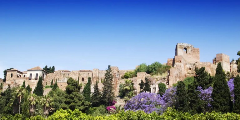 Ancient stone fortress with trees and blue sky background.