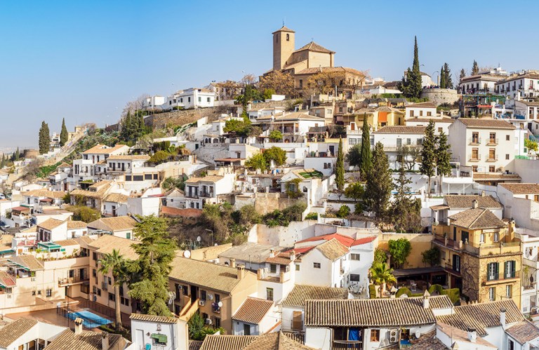 Hillside town with clustered white buildings and a church at the top.